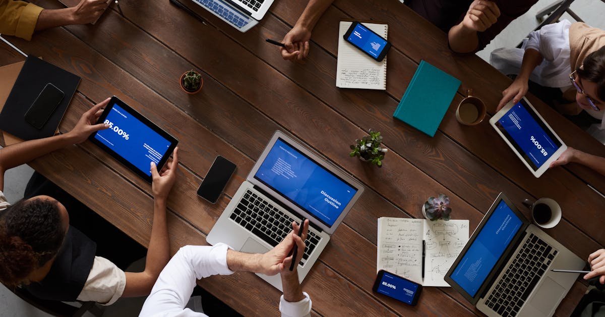 Overhead view of team collaborating on pitch decks across laptops and tablets - AI creative tools enabling rapid iteration
